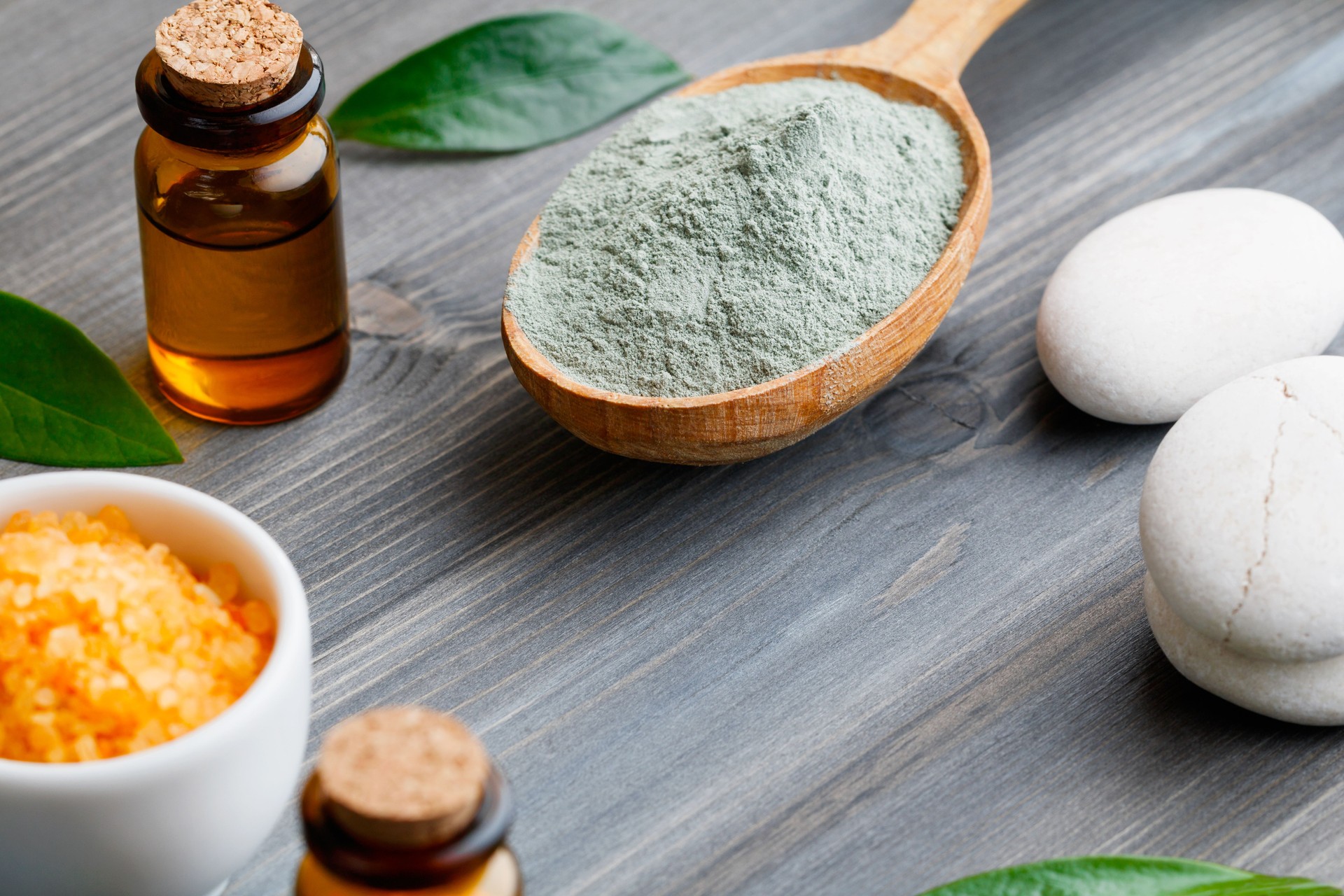 Close-up spa cosmetic products - clay, oil and sea salt on a wooden background.