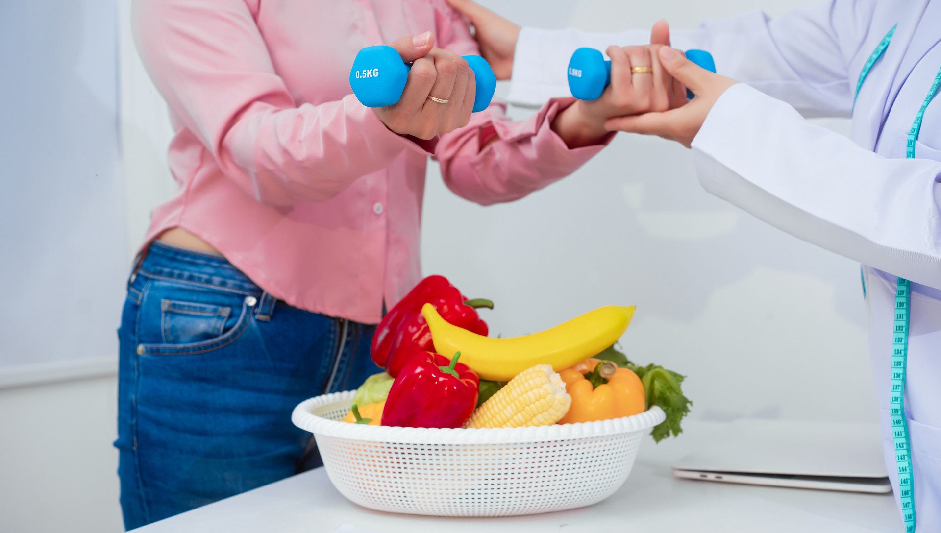 A middle aged Asian female nutritionist consults with a middle aged Asian female patient at a table, discussing nutrition, healthy eating, exercise, and lifestyle changes for weight loss and health
