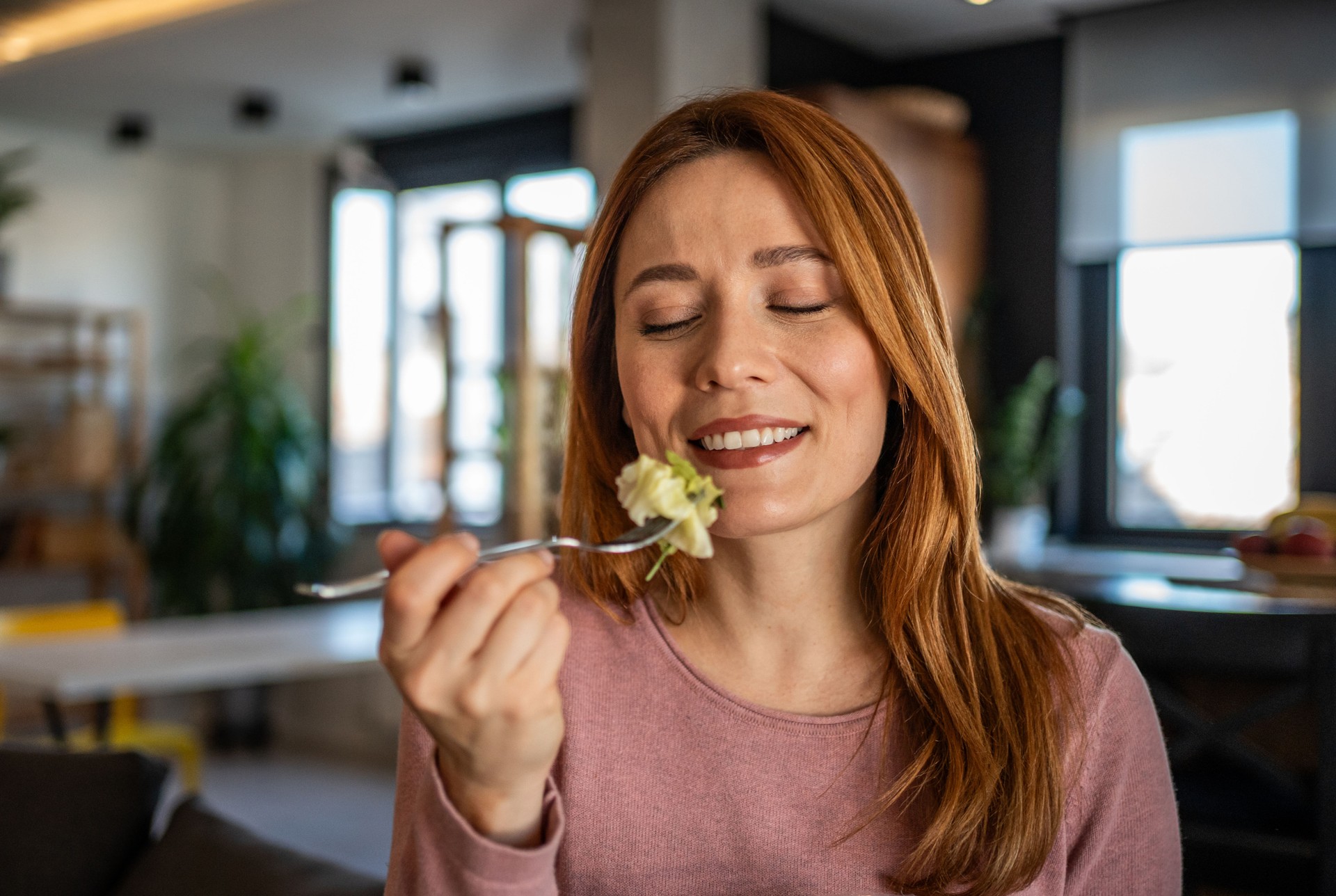 Happy woman eating fresh salad at home, enjoying healthy lifestyle